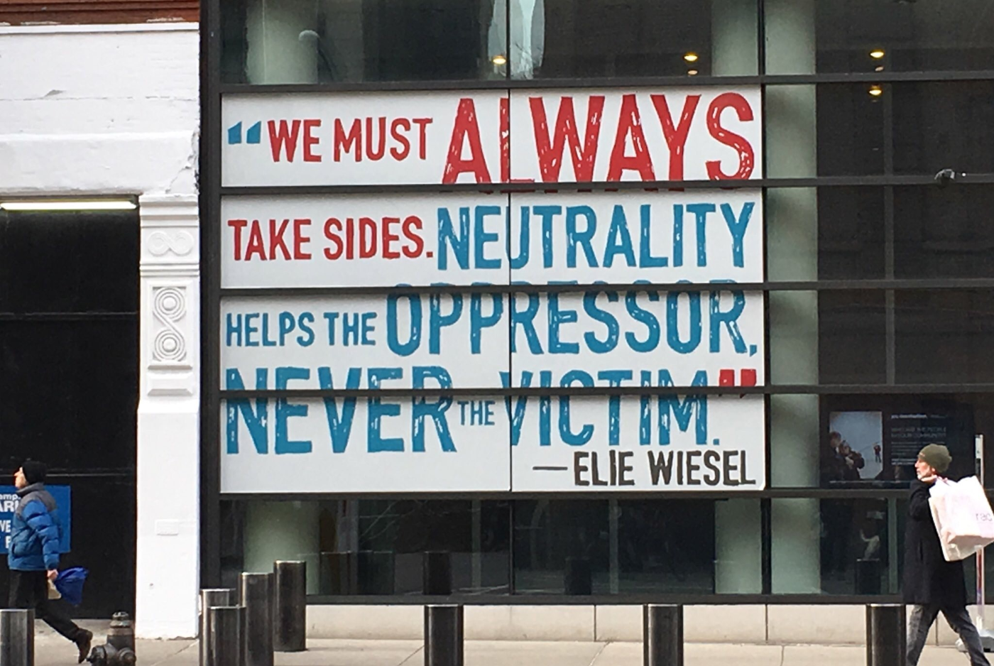 Poster in a window: We must always take sides. Neutrality helps the oppressor, never the victim. Elie Wiesel.