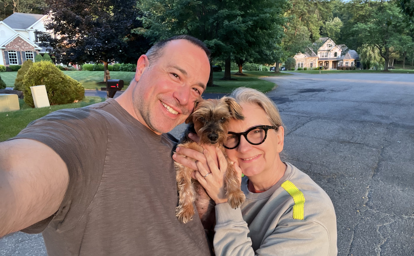 Ben and Mary Kate holding Lucy between their faces in a golden hour photo.